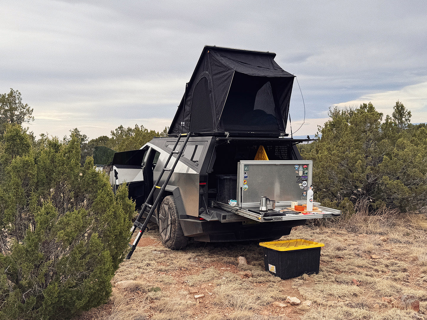 Cybertruck camper with a rooftop tent, bed slide, and camp kitchen in a natural setting